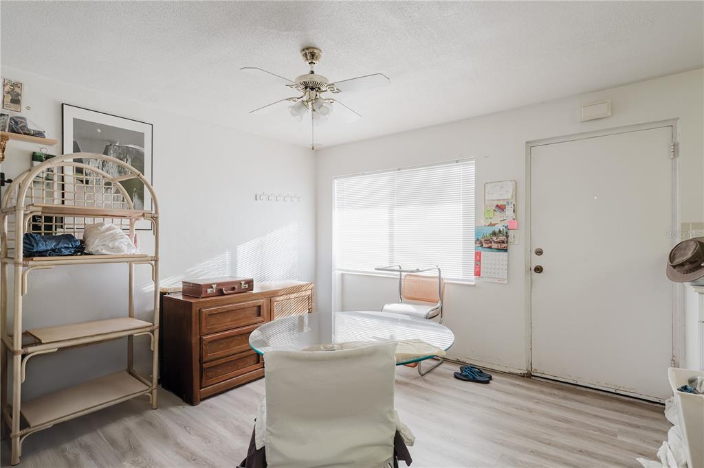 A dining area features a glass-topped table, wooden dresser, rattan shelving unit, and ceiling fan — 8950 PARK BOULEVARD UNIT 702, SEMINOLE, FL