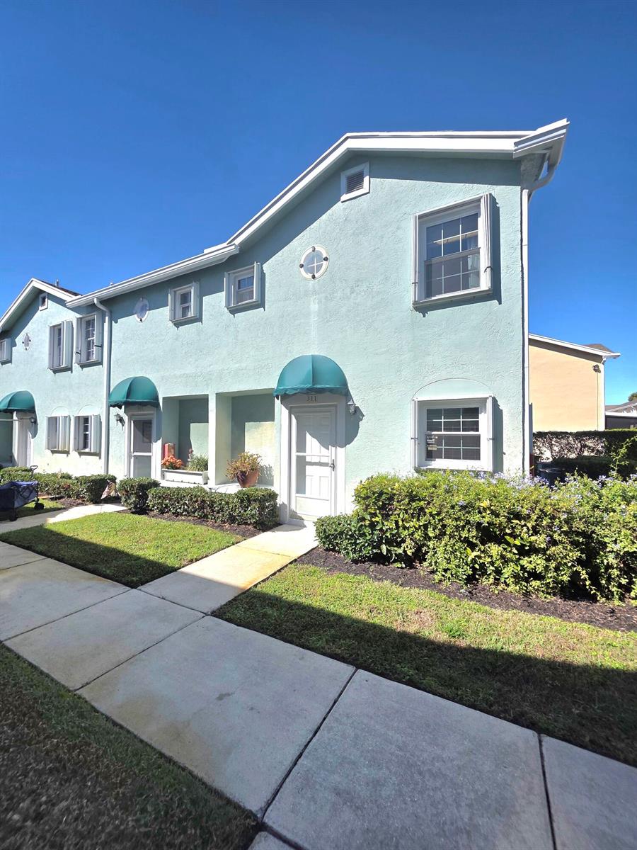 A light blue two-story townhouse exterior features green awnings over the front doors — 311 Waterside Drive # 9c, Hypoluxo FL 33462, HYPOLUXO, FL