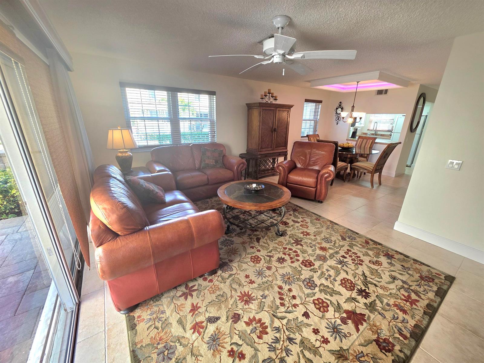 A living room with leather furniture, a floral rug, and an adjacent dining area — 311 Waterside Drive # 9c, Hypoluxo FL 33462, HYPOLUXO, FL