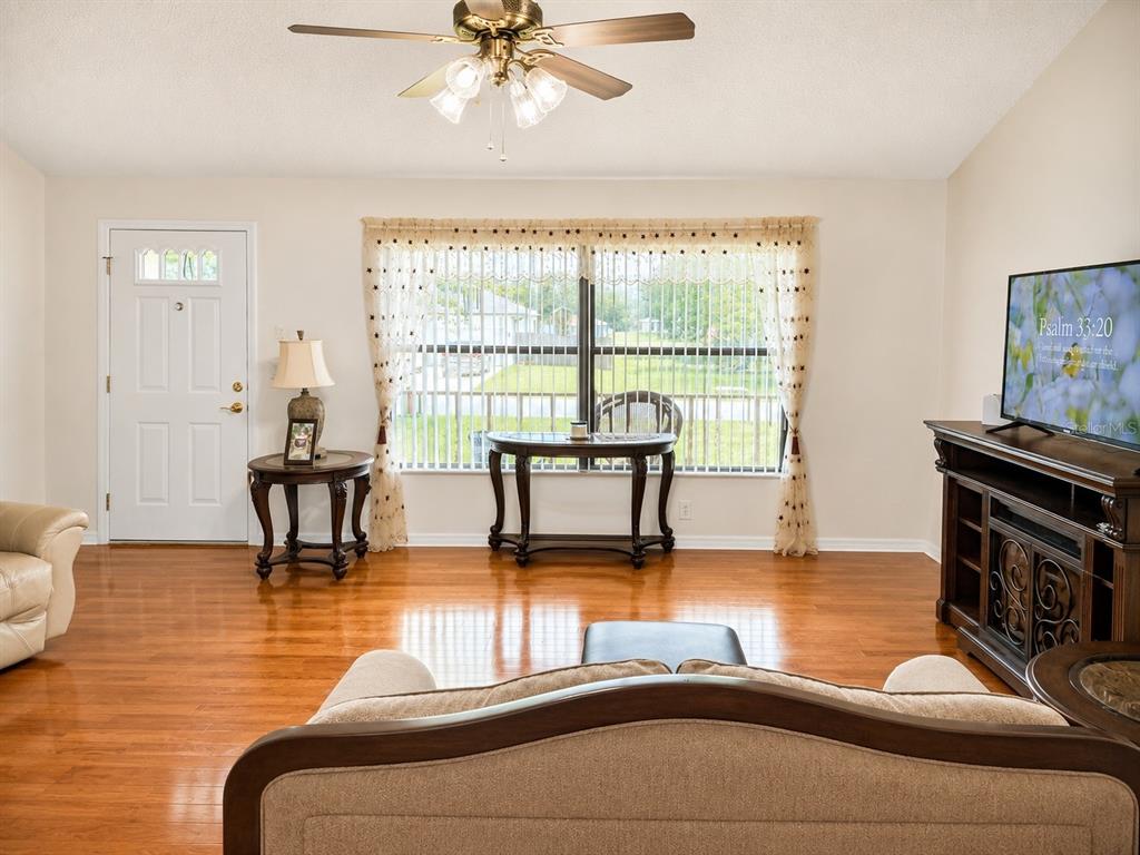A living room features hardwood floors, a ceiling fan, a television, and a front door — 4276 SW 140TH STREET ROAD, OCALA, FL