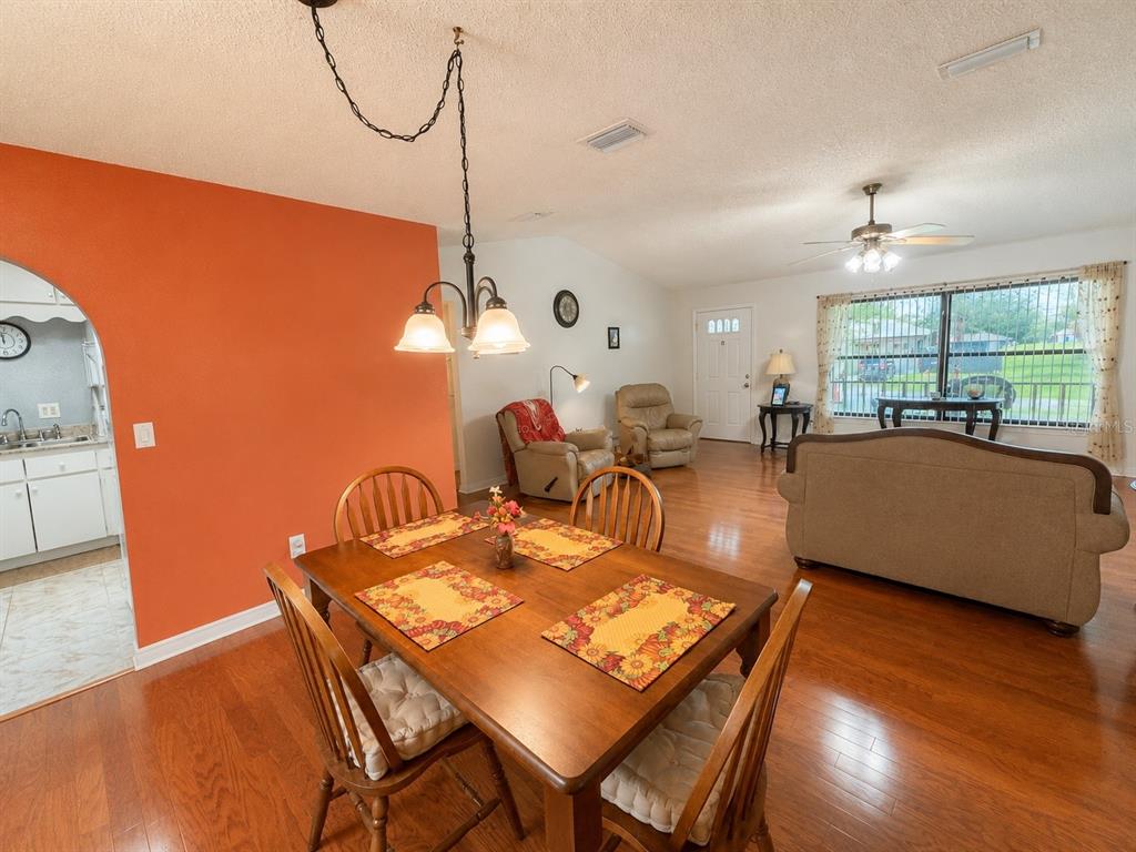 A dining area with a wooden table and chairs sits in front of a living room — 4276 SW 140TH STREET ROAD, OCALA, FL