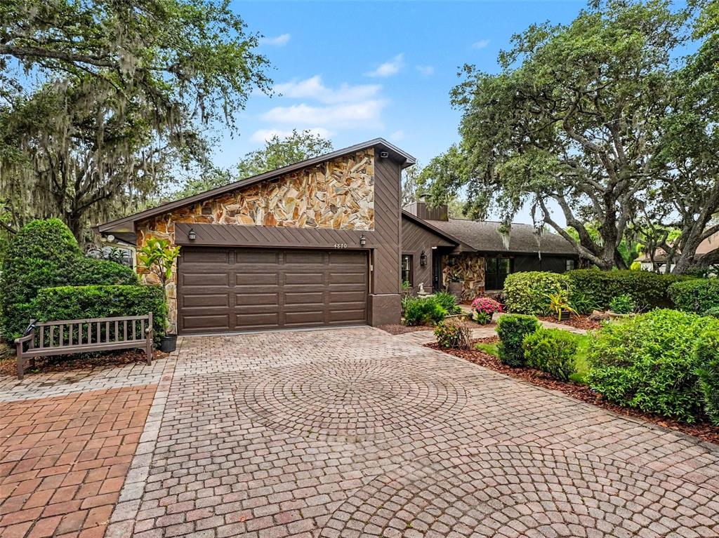 A house with a stone facade, brown garage door, and a circular brick driveway — 4870 CITRUS OAK LANE, ST CLOUD, FL