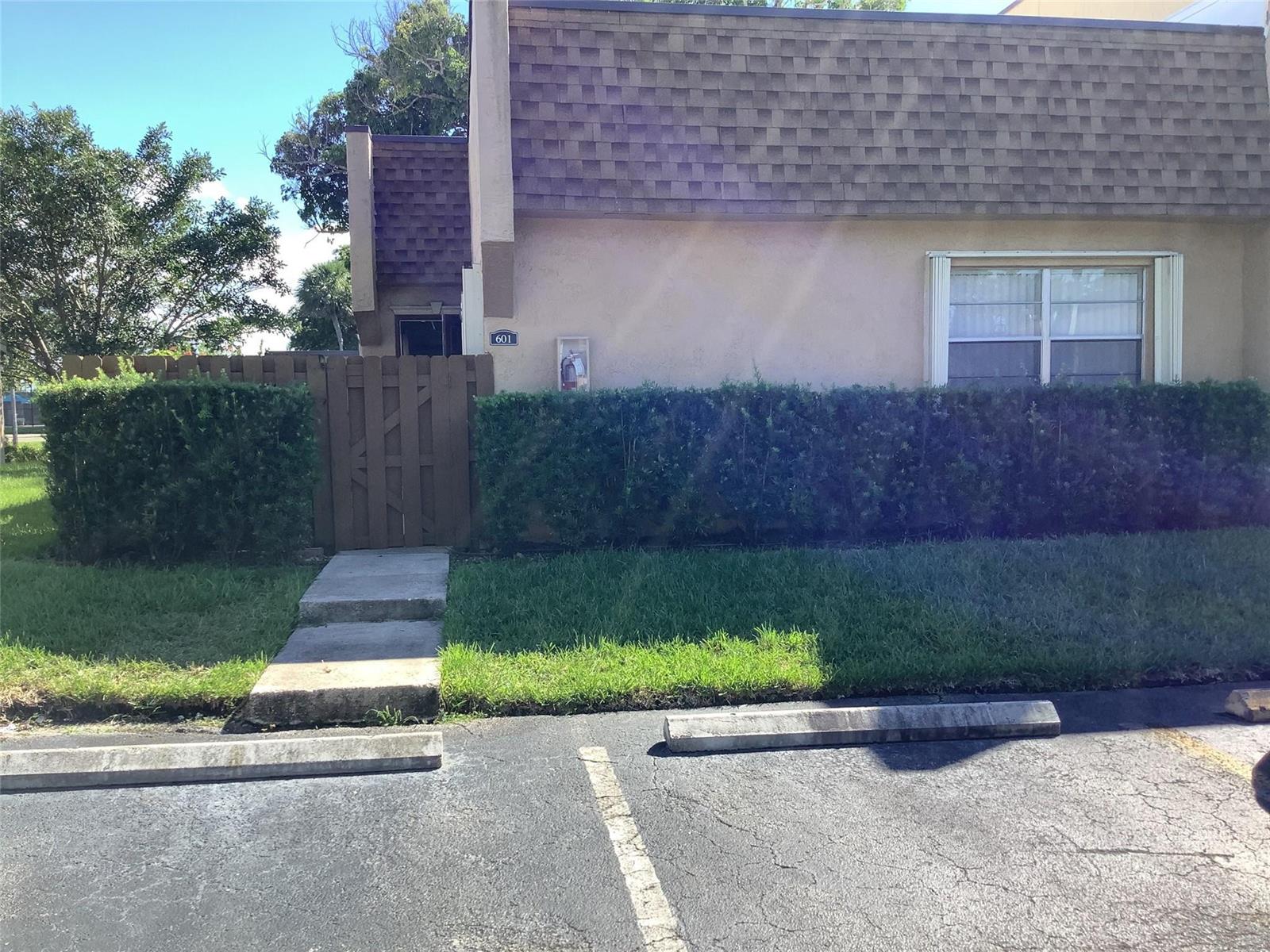 A tan building exterior features a wooden gate, a small window, and a concrete walkway — 3581 NW 95th Terrace # 601, Sunrise FL 33351, SUNRISE, FL