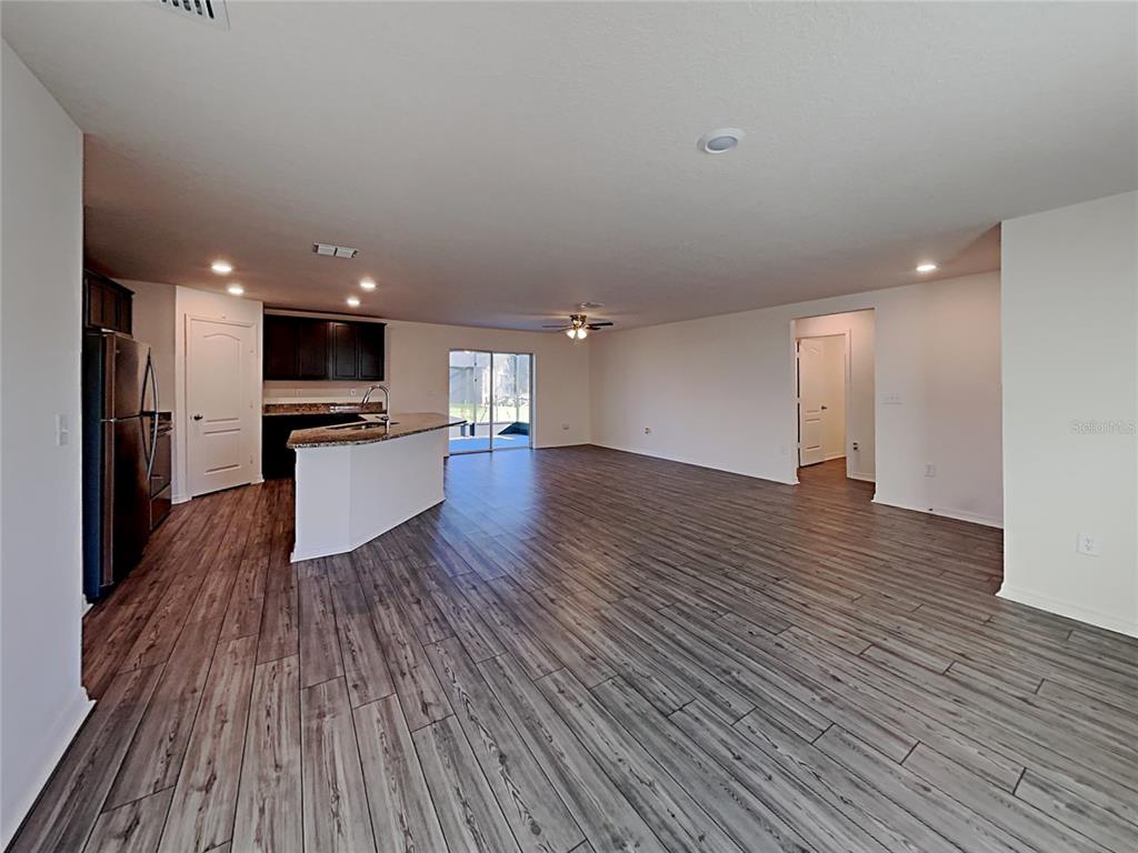 An open-concept kitchen and living area feature dark wood cabinets, granite countertops, and wood-look flooring — 424 OHIO LANE, KISSIMMEE, FL