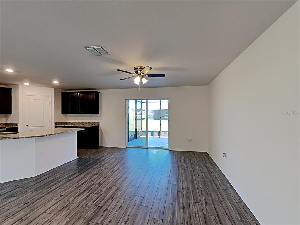 An open-concept living area features wood-look tile flooring, a ceiling fan, and a kitchen island — 424 OHIO LANE, KISSIMMEE, FL