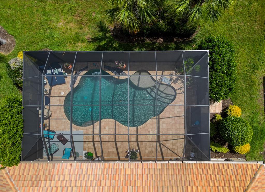An aerial view shows a screened-in swimming pool with a paver patio and surrounding landscaping — 19168 JALISCA STREET, VENICE, FL