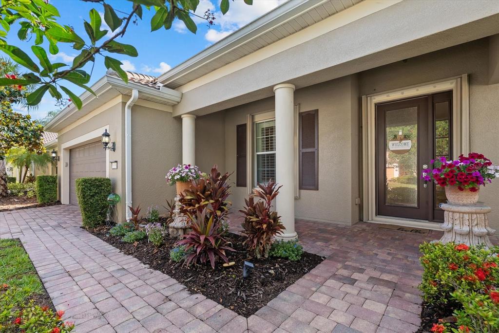 A paved walkway leads to the front entrance of a house with two white columns — 19168 JALISCA STREET, VENICE, FL