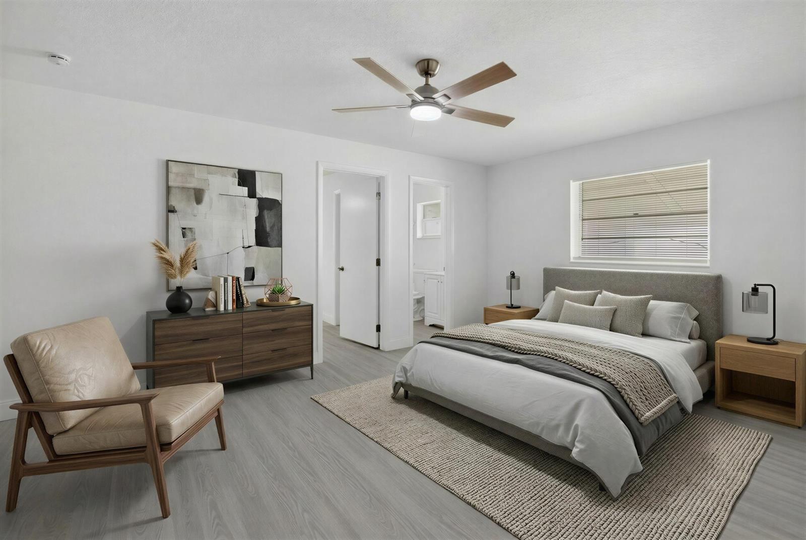 A bedroom features light wood-look flooring, a gray upholstered bed, a dresser, and an armchair — 703 SW 18th Street, Boynton Beach FL 33426, BOYNTON BEACH, FL