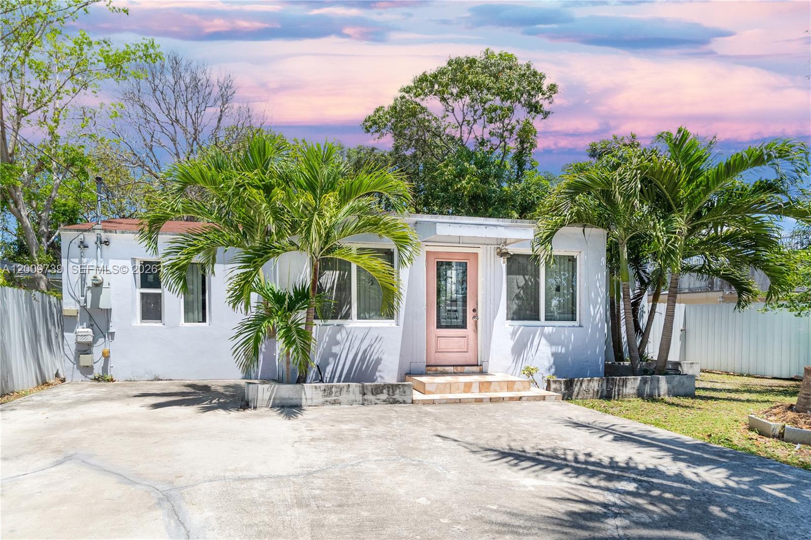 A single-story house with a pink front door, palm trees, and a concrete driveway — 235 NW 59th St, Miami FL 33127, MIAMI, FL