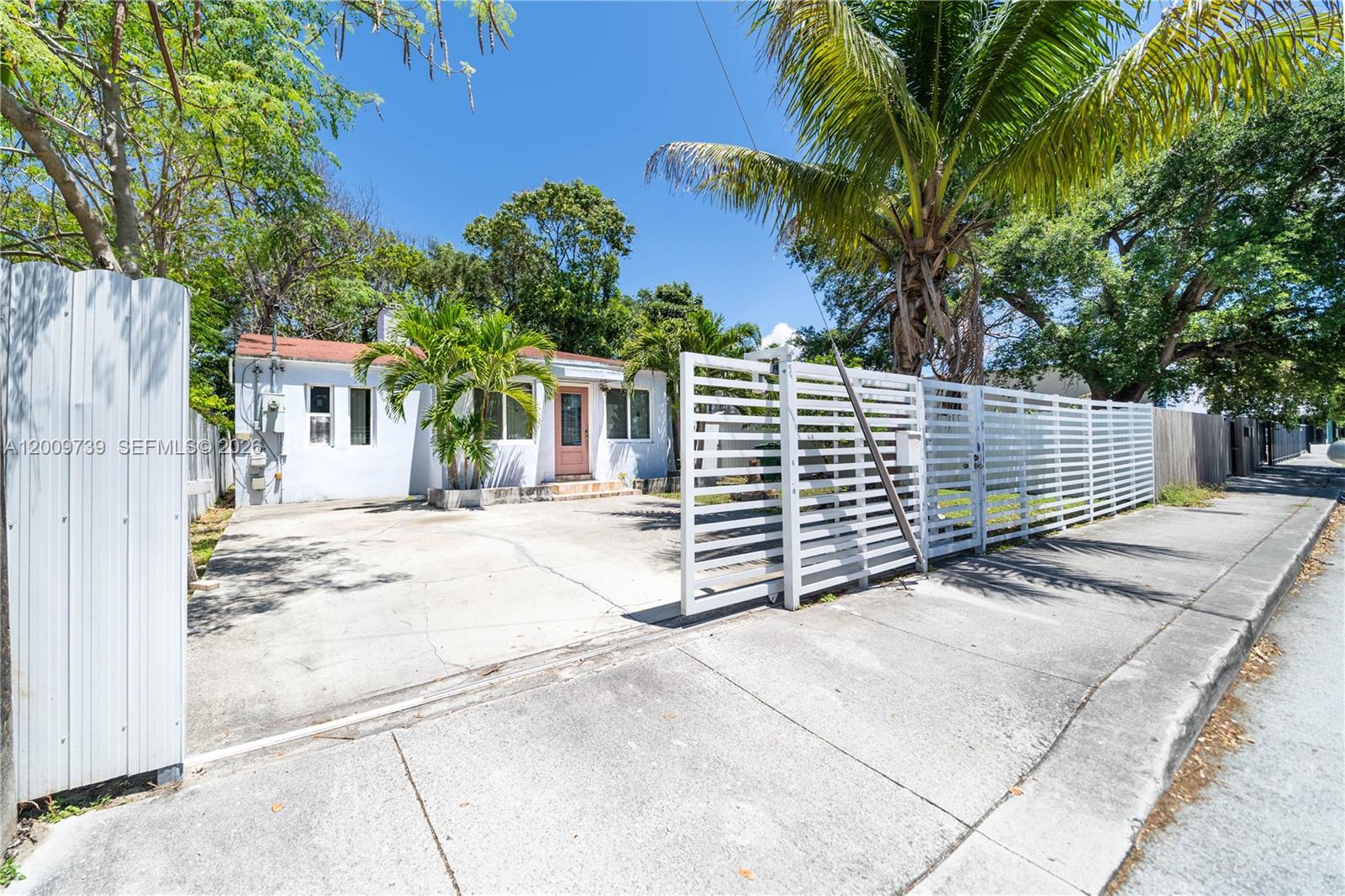 A single-story house with a concrete driveway and a white horizontal-slat fence — 235 NW 59th St, Miami FL 33127, MIAMI, FL