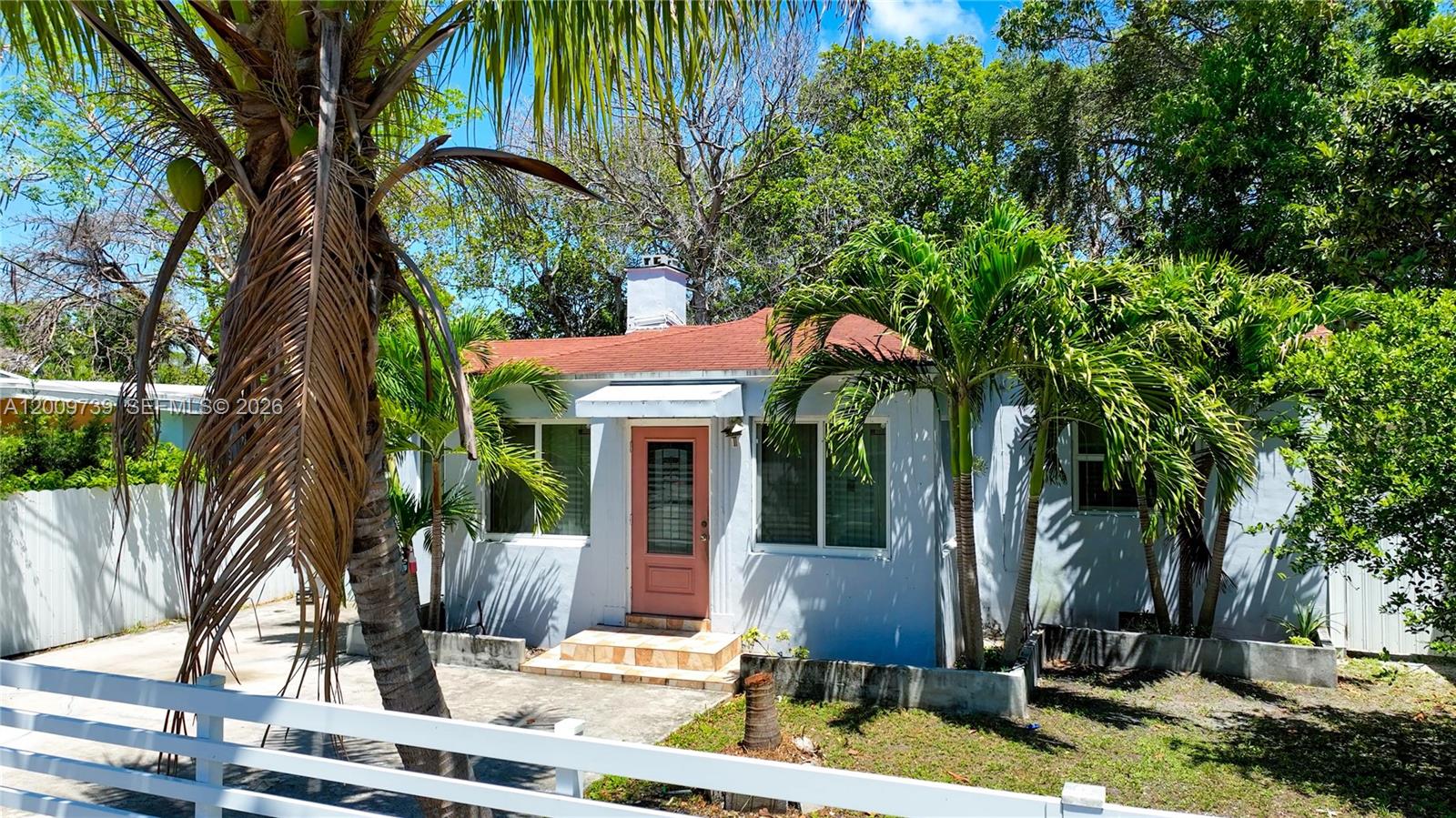 A single-story house with a pink door, white siding, and palm trees in the front yard — 235 NW 59th St, Miami FL 33127, MIAMI, FL