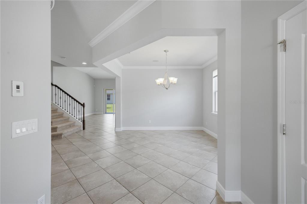 A tiled entryway leads to a dining area with a chandelier and a staircase — 6023 W TOWN CENTER BOULEVARD, ORLANDO, FL