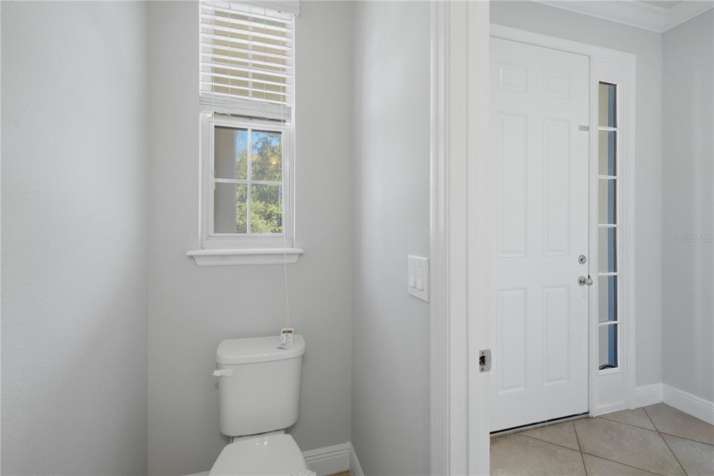 A small bathroom with a toilet and window next to a white exterior door — 6023 W TOWN CENTER BOULEVARD, ORLANDO, FL