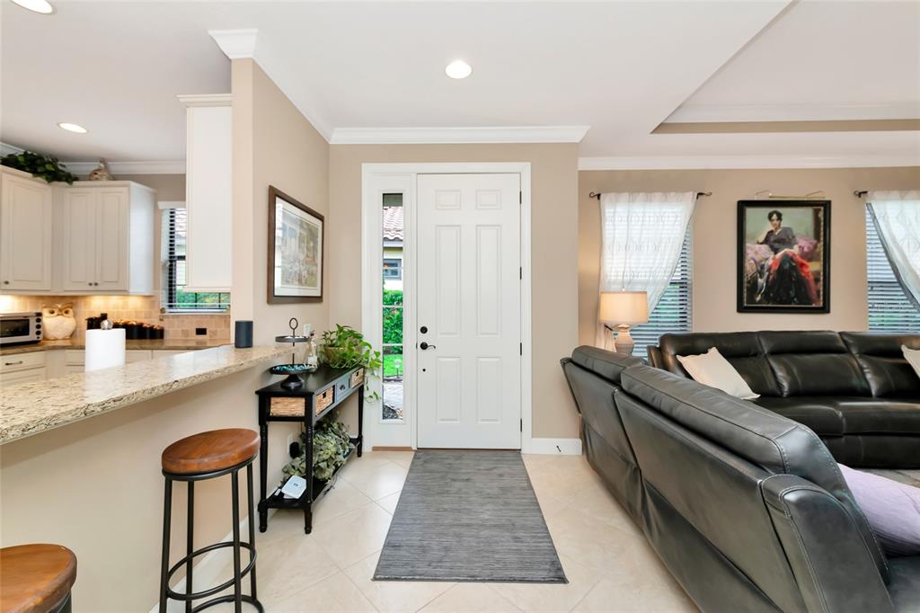 An entryway with a white door, tile floors, and a view into the adjacent kitchen — 5126 SAVONA RUN, BRADENTON, FL