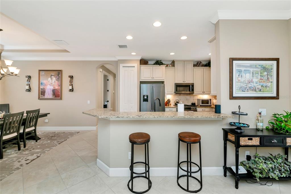 A kitchen with a granite breakfast bar, two stools, and light-colored cabinetry — 5126 SAVONA RUN, BRADENTON, FL