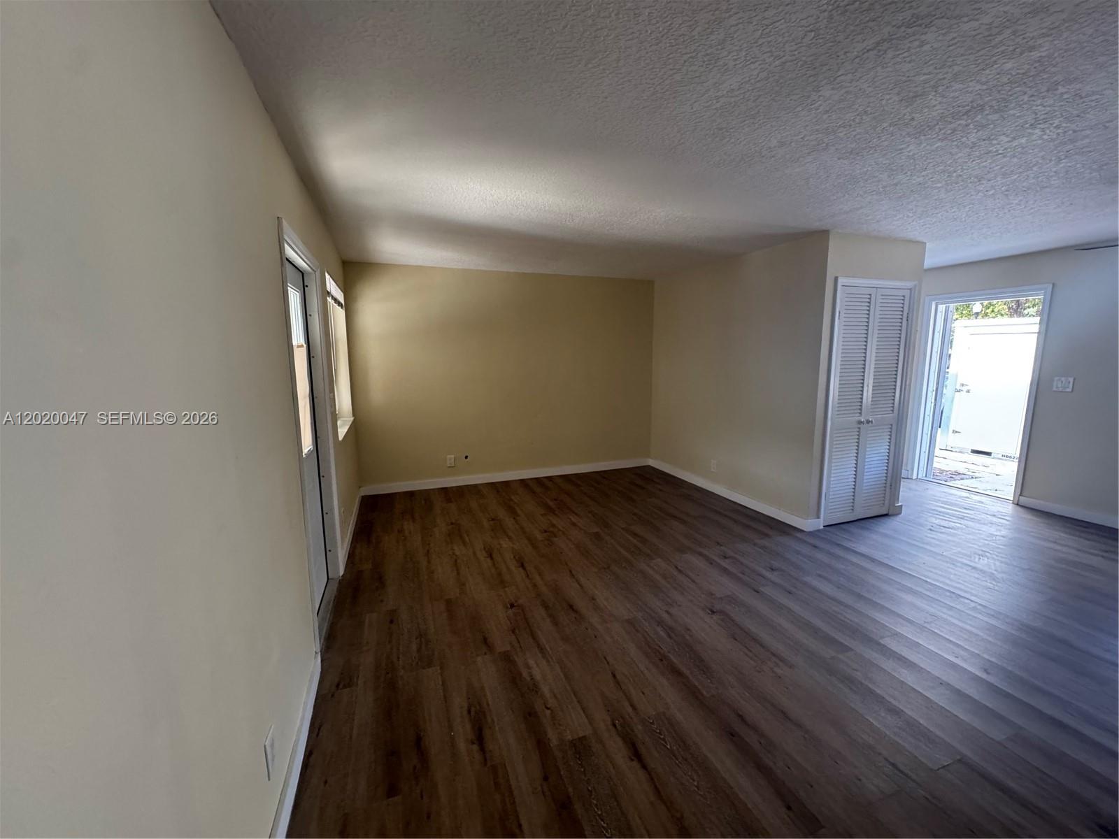 An empty room features light-colored walls, dark wood-look flooring, a closet, and two doorways — 707 S 19th Ave # 2, Hollywood FL 33020, HOLLYWOOD, FL