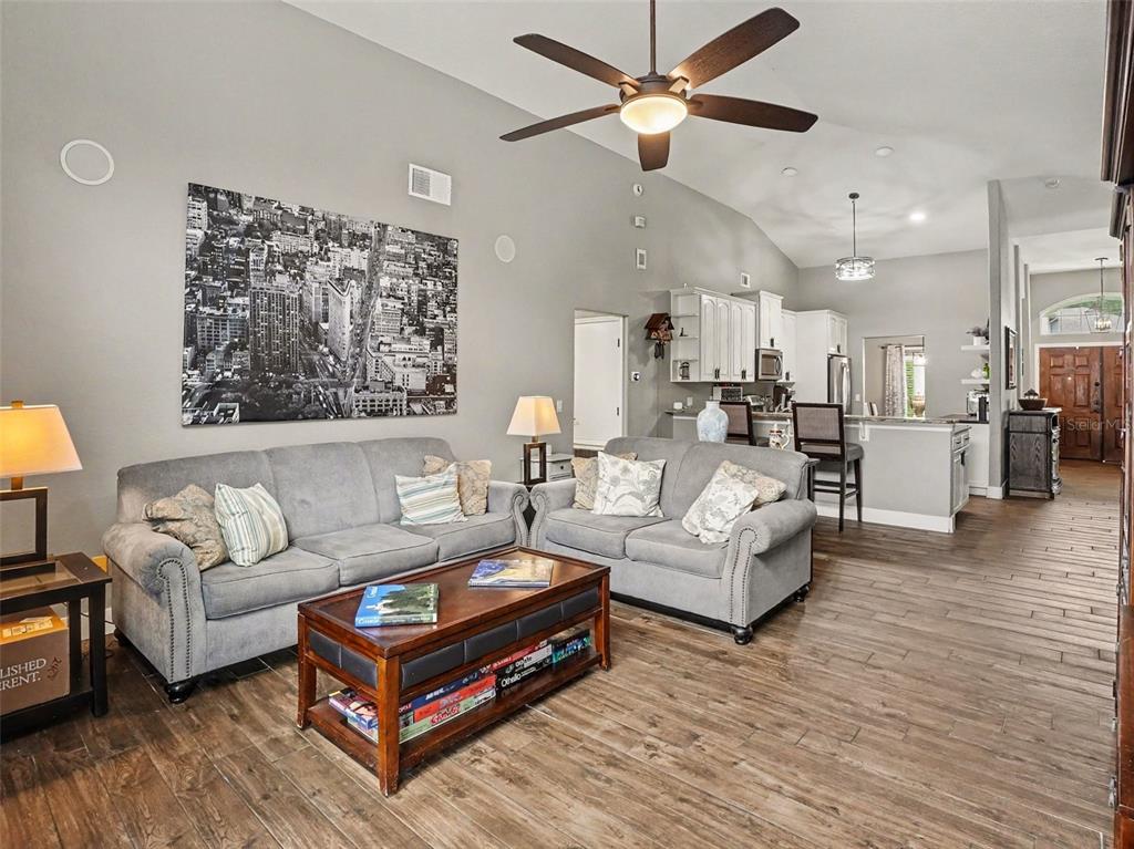 A living room with gray sofas, a coffee table, and an open kitchen in the background — 5638 CATSKILL COURT, WINTER SPRINGS, FL