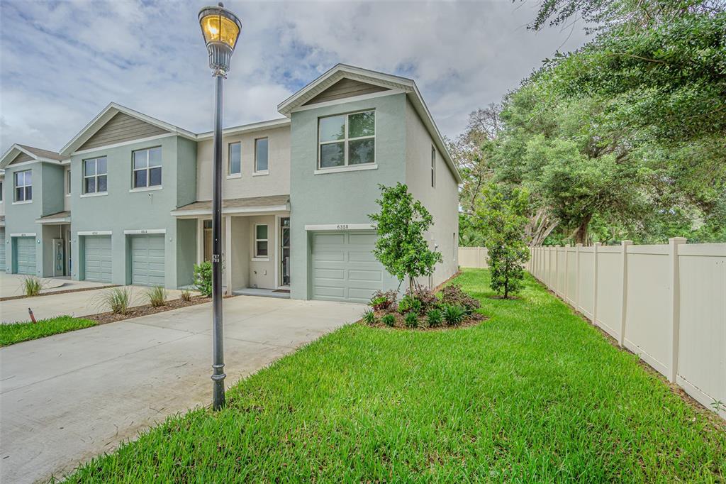 A two-story townhouse with a light green exterior, a single-car garage, and a side yard — 6358 SOPHIE OAKS COURT, TAMPA, FL
