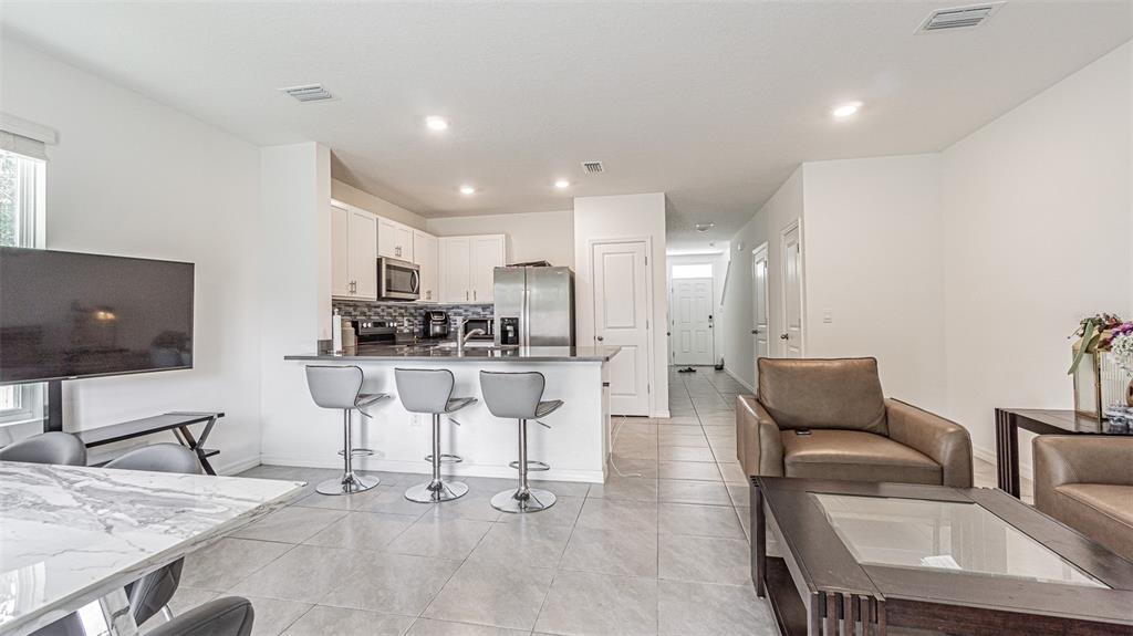 An open-concept kitchen with a breakfast bar overlooks a living area with tile flooring — 6358 SOPHIE OAKS COURT, TAMPA, FL