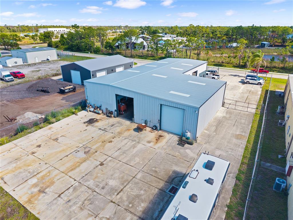 An aerial view shows a metal warehouse building with a large concrete parking lot — 2640 AVENUE OF THE AMERICAS, ENGLEWOOD, FL