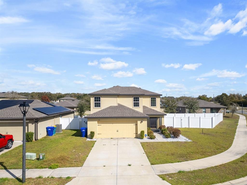 A two-story yellow house with a two-car garage and a white vinyl fence — 1136 SEA PINES COURT, TAVARES, FL