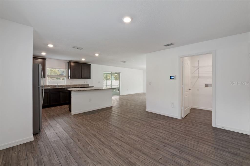 An open-concept kitchen with dark cabinets and a pantry overlooks a spacious living area — 1136 SEA PINES COURT, TAVARES, FL