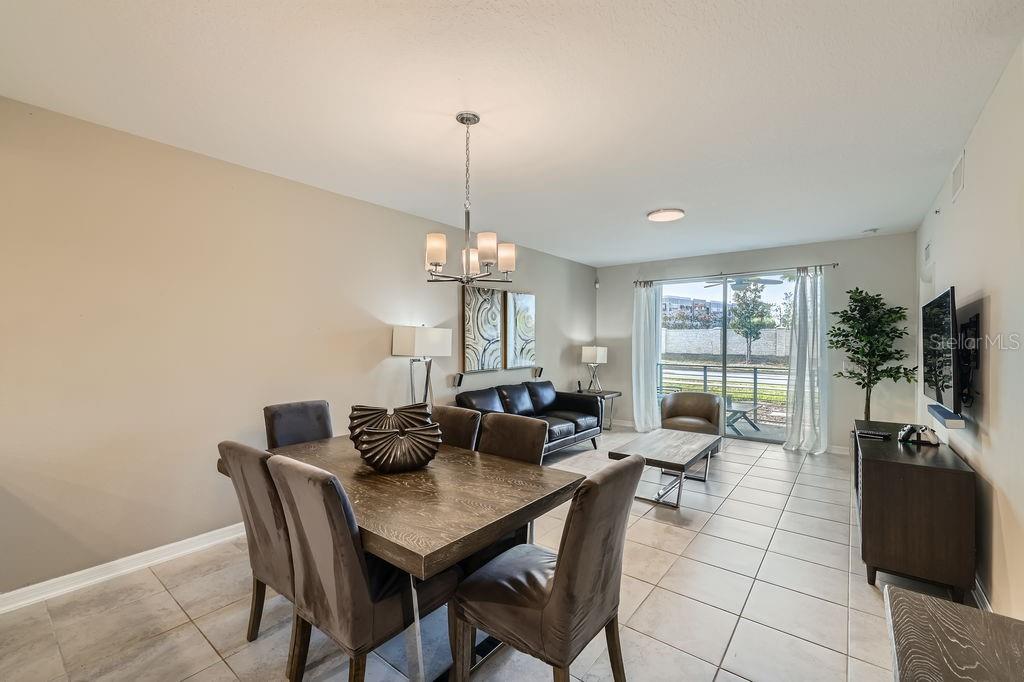 A dining area and living room with tile floors, a chandelier, and sliding glass doors — 4731 CLOCK TOWER DRIVE UNIT 104, KISSIMMEE, FL