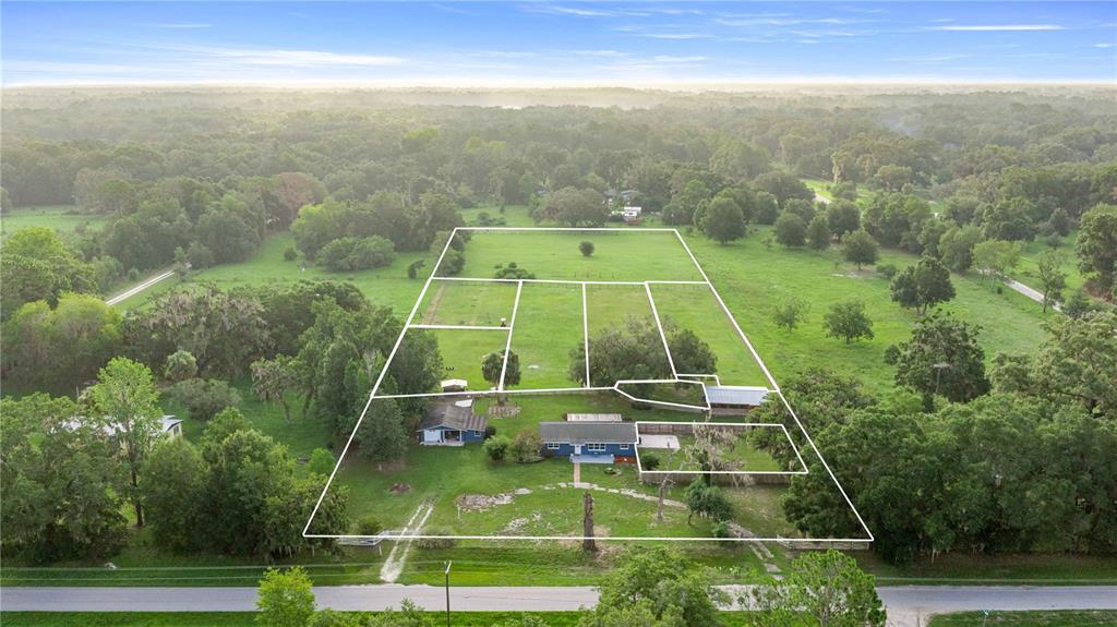 An aerial view shows a house and outbuildings on a large, fenced rural property — 15027 SW 91ST STREET, ARCHER, FL