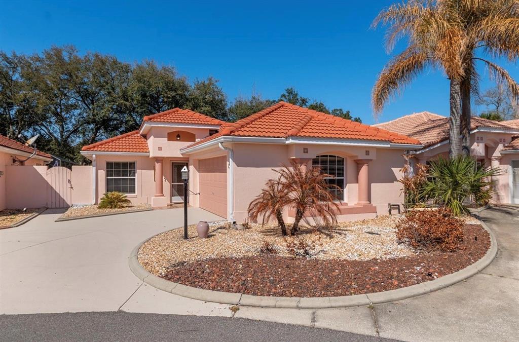 A single-story peach-colored house with a red tile roof and a circular gravel front yard — 1305 SANTA MARIA AVENUE, LADY LAKE, FL