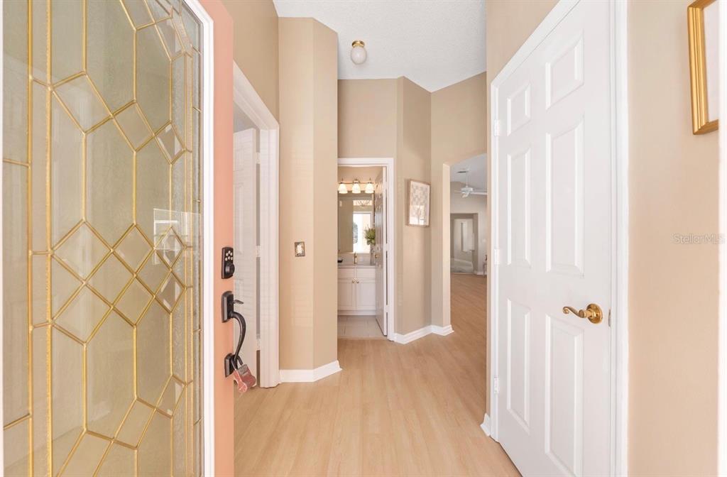 A bright entryway features light wood-look flooring, beige walls, and white interior doors — 1305 SANTA MARIA AVENUE, LADY LAKE, FL