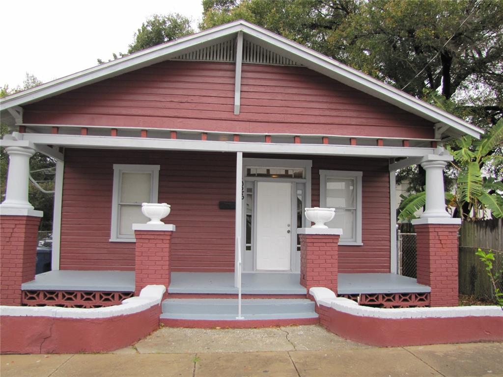 A red-painted house with a front porch, brick columns, and a white front door — 1026 E 15TH AVENUE, TAMPA, FL