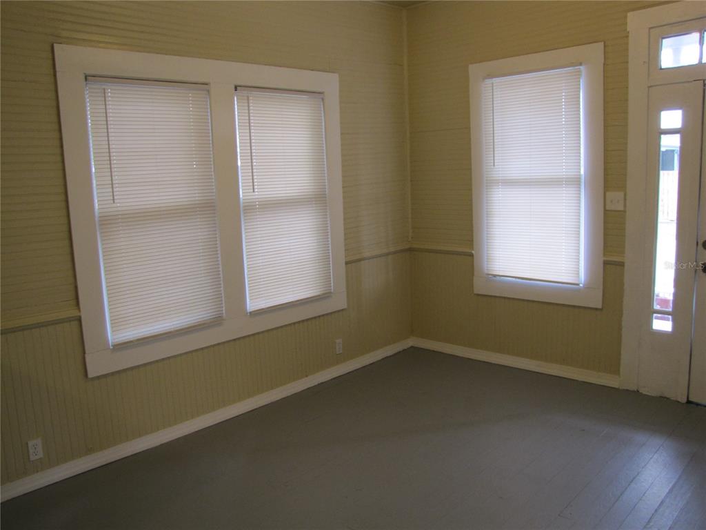 An interior room with light-colored walls, gray flooring, white trim, and several windows — 1026 E 15TH AVENUE, TAMPA, FL