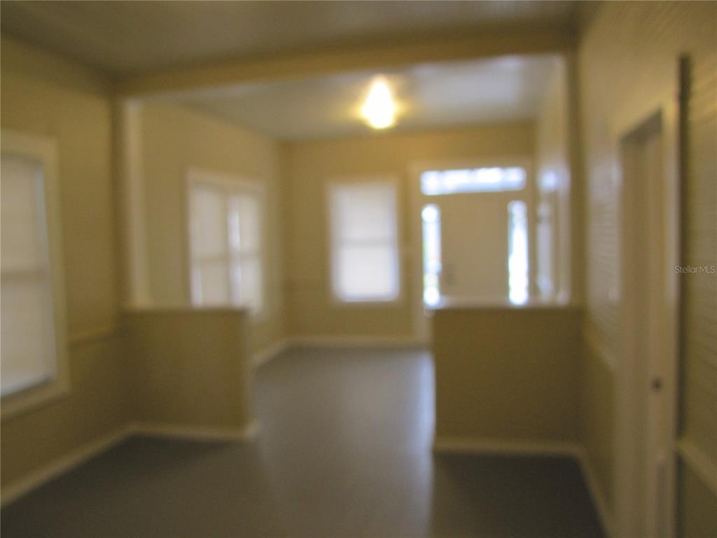 An interior view shows a living area with light-colored walls and a partial wall divider — 1026 E 15TH AVENUE, TAMPA, FL