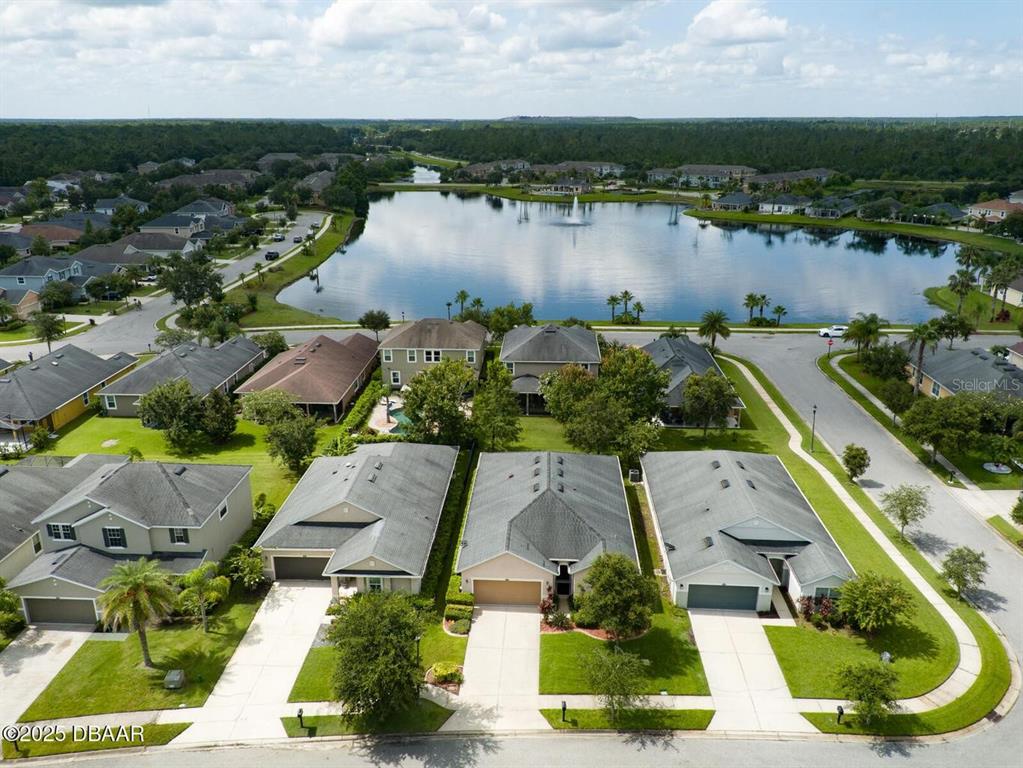 An aerial view shows several suburban houses situated near a large lake with a fountain — 145 PRESTWICK GRANDE DRIVE, DAYTONA BEACH, FL