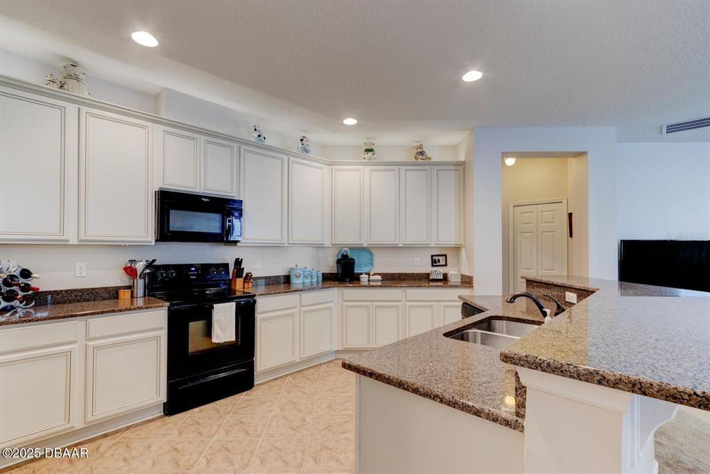 A kitchen features white cabinets, granite countertops, and black appliances — 145 PRESTWICK GRANDE DRIVE, DAYTONA BEACH, FL