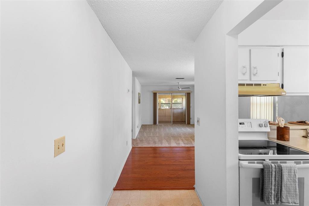 A view from a kitchen looking through a hallway toward a living area and patio — 3 FAIRWAY COURT, DELAND, FL