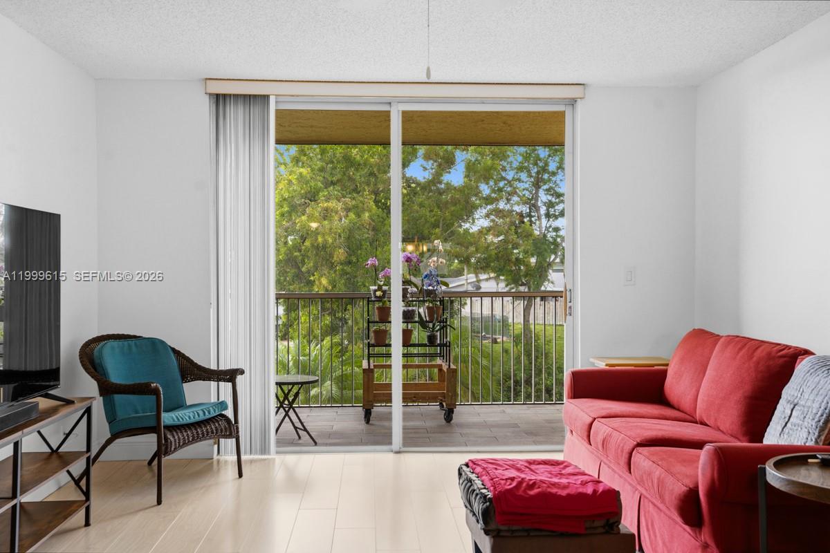A living room features a red sofa, a wicker chair, and a sliding glass door — 6870 Royal Palm Blvd # 209M, Margate FL 33063, MARGATE, FL