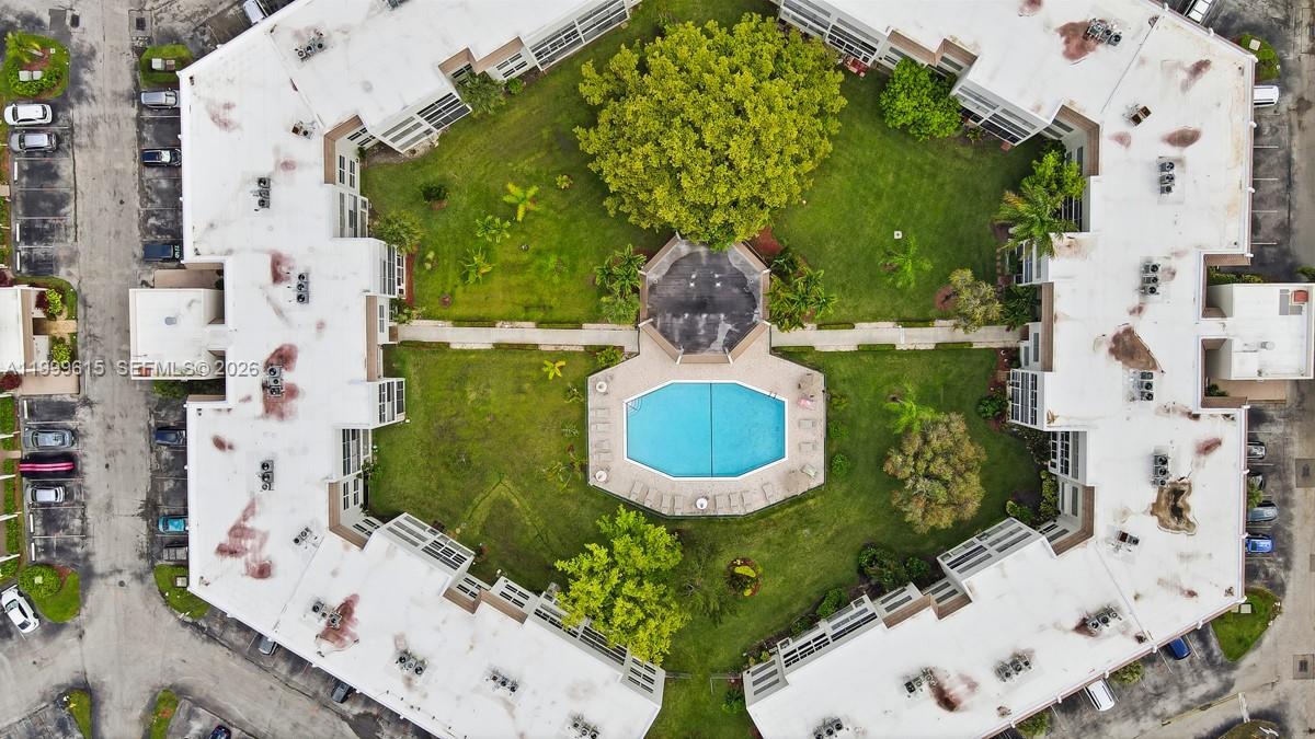An aerial view shows a multi-story apartment complex surrounding a central courtyard with a pool — 6870 Royal Palm Blvd # 209M, Margate FL 33063, MARGATE, FL