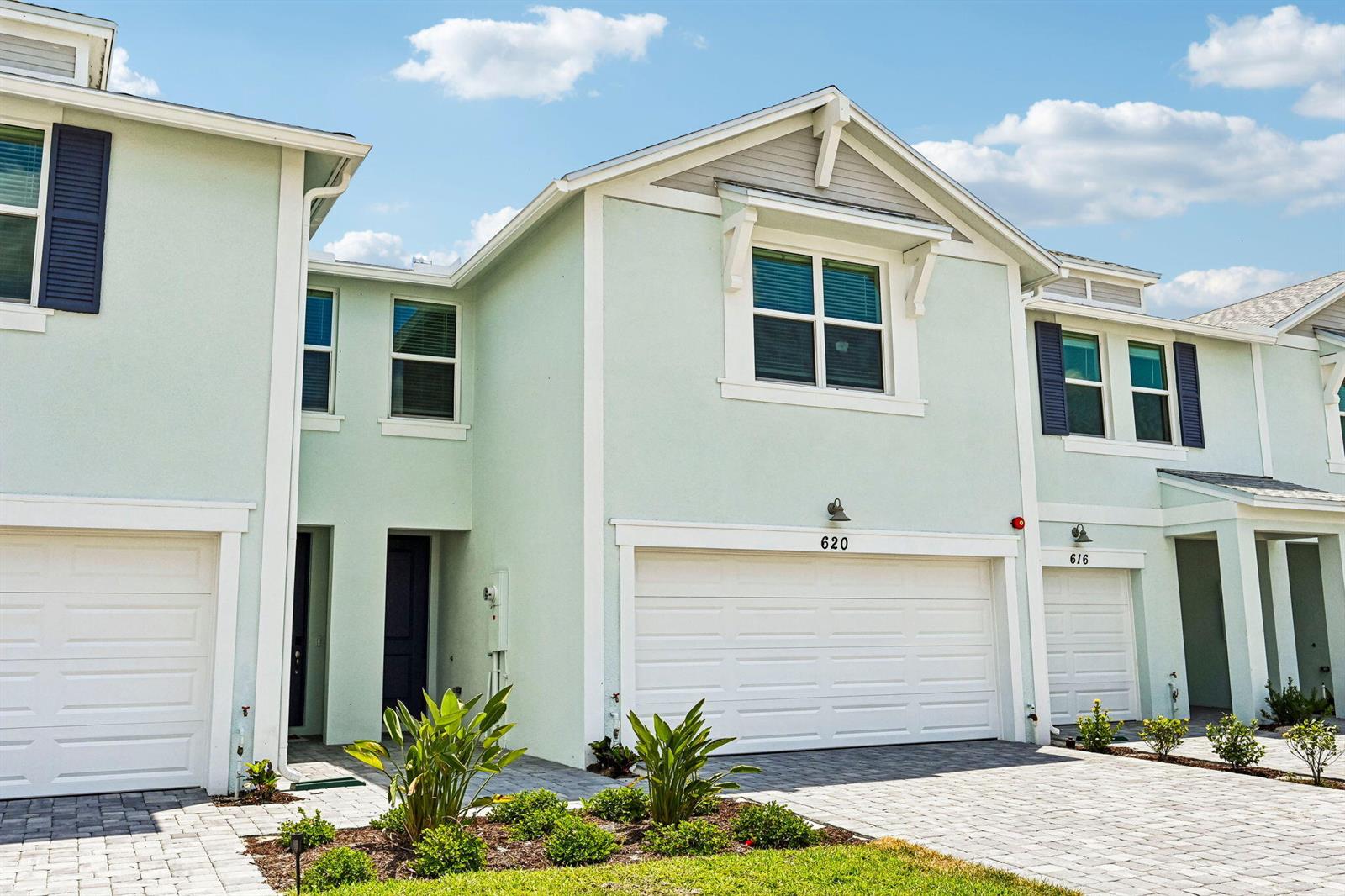 A light green multi-story townhouse exterior features white trim, garage doors, and a paved driveway — 620 Salisbury Circle, Fort Pierce FL 34982, FORT PIERCE, FL