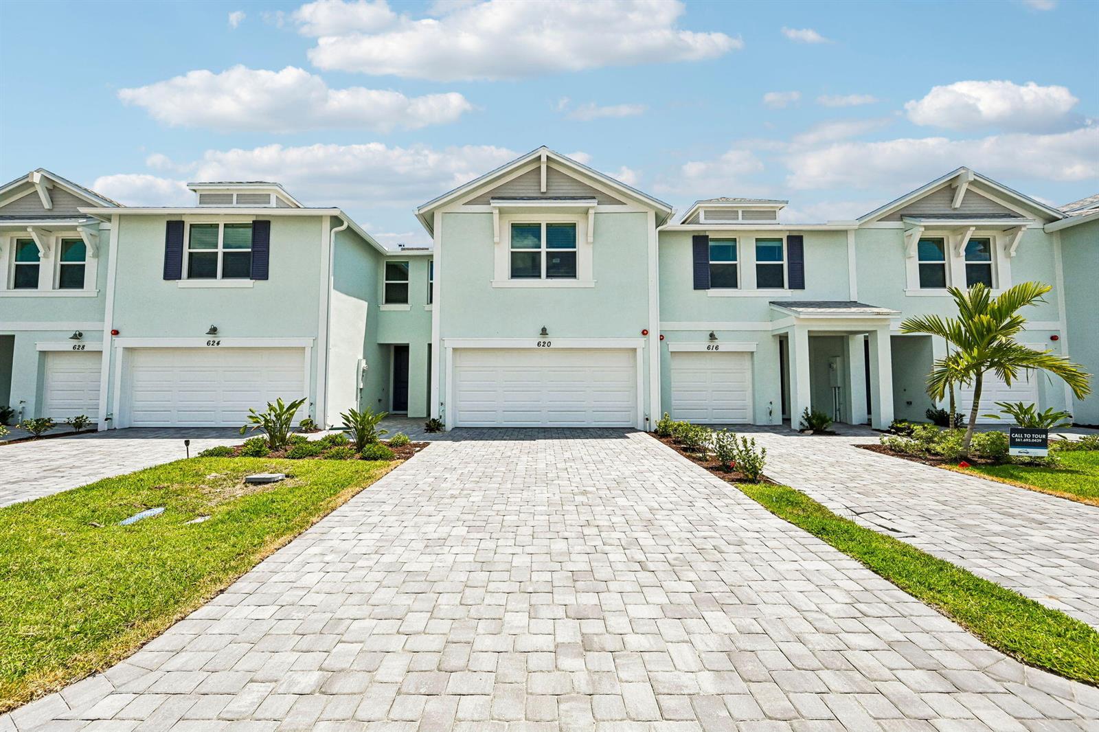 A row of light green townhouses features paved driveways, white garage doors, and blue shutters — 620 Salisbury Circle, Fort Pierce FL 34982, FORT PIERCE, FL