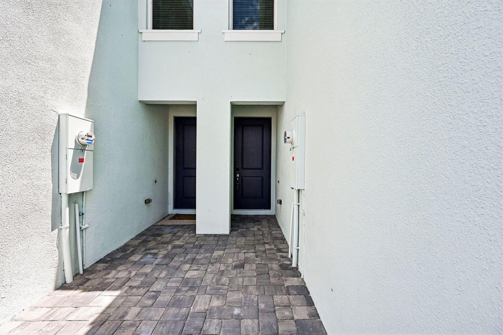 A paved entryway leads to two dark front doors set into a light-colored stucco building — 620 Salisbury Circle, Fort Pierce FL 34982, FORT PIERCE, FL