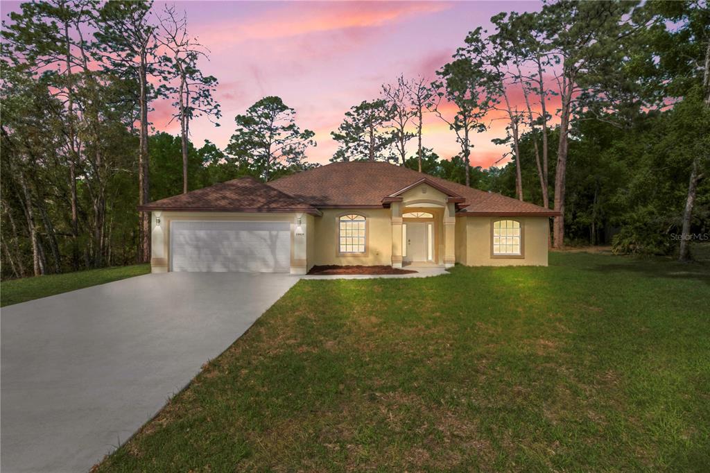 A single-story house with a beige stucco exterior, a two-car garage, and a concrete driveway — 19939 SW 96TH PLACE, DUNNELLON, FL
