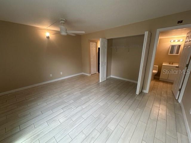 A bedroom with light-colored tile flooring, a ceiling fan, a closet, and an attached bathroom — 4131 DOLPHIN DRIVE UNIT 4131, TAMPA, FL