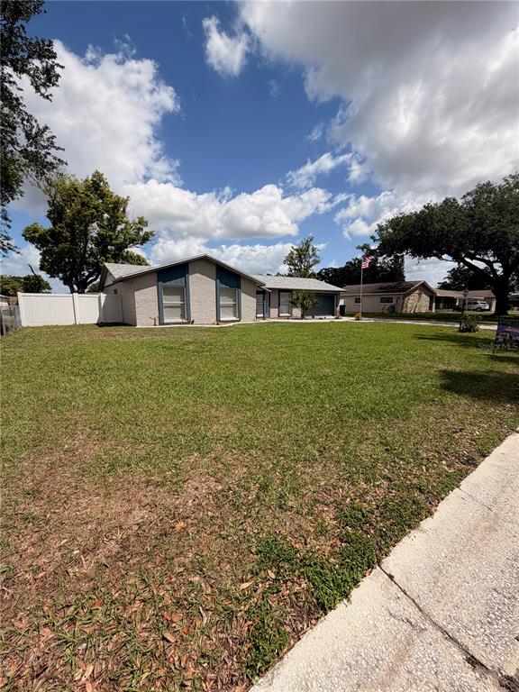 A single-story house with a light-colored exterior sits on a large, grassy lot — 1210 LADY ELAINE DRIVE, VALRICO, FL