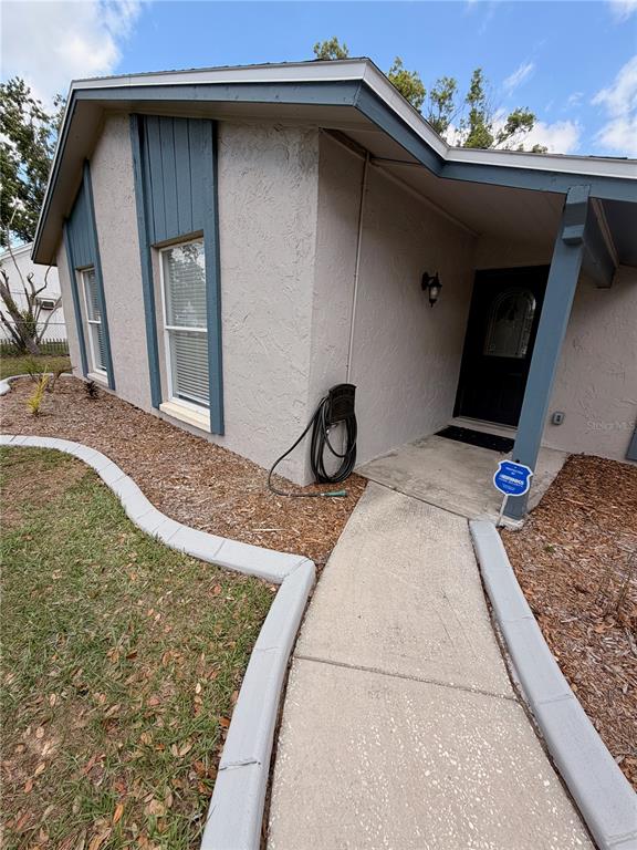 A concrete walkway leads to the front entrance of a house with stucco exterior walls — 1210 LADY ELAINE DRIVE, VALRICO, FL