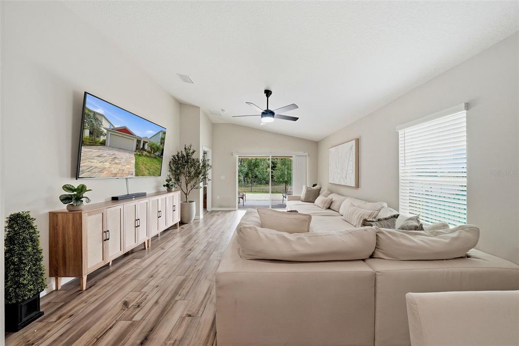 A living room features a large sectional sofa, a media console, and a wall-mounted television — 5560 SUMMER SUNSET DRIVE, APOLLO BEACH, FL