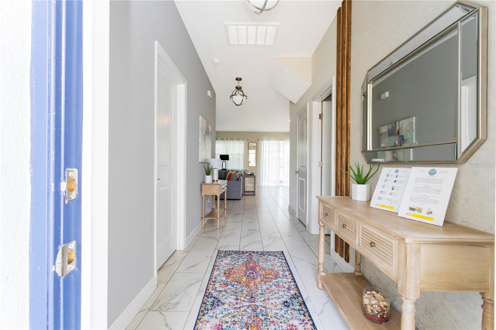 A bright entryway features white tile floors, a colorful runner, and a wooden console table — 1520 FLANGE DRIVE, DAVENPORT, FL