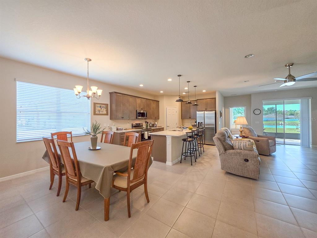 An open-concept kitchen, dining area, and living room featuring tile floors and neutral walls — 8 LAKELAND WAY, PALM COAST, FL