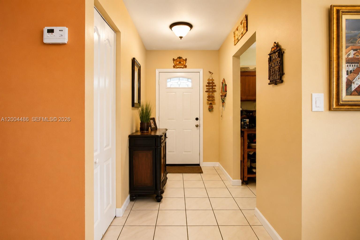 A tiled entryway features a white front door, a dark wood console, and yellow walls — 15071 SW 127th Ct, Miami FL 33186, MIAMI, FL