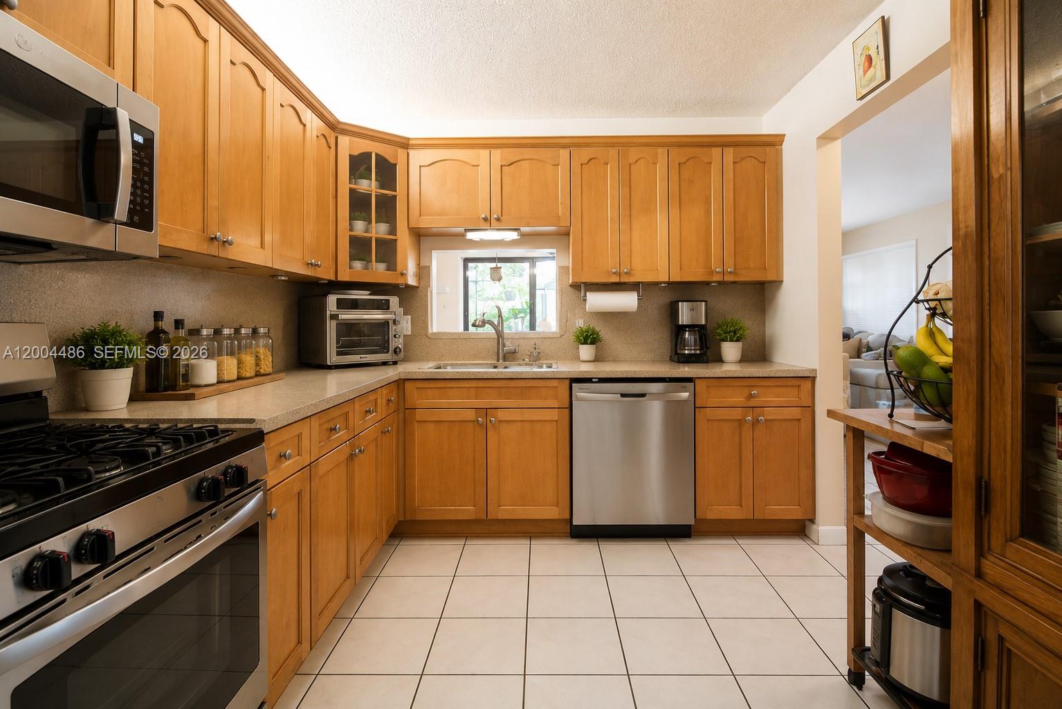 A kitchen with light wood cabinets, stainless steel appliances, and white tiled flooring — 15071 SW 127th Ct, Miami FL 33186, MIAMI, FL